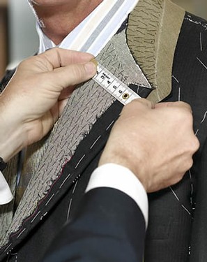 an image of a tailored jacket exposing the lapel fusings. A tape measure runs accross the lapel to get the exact size needed for alteration